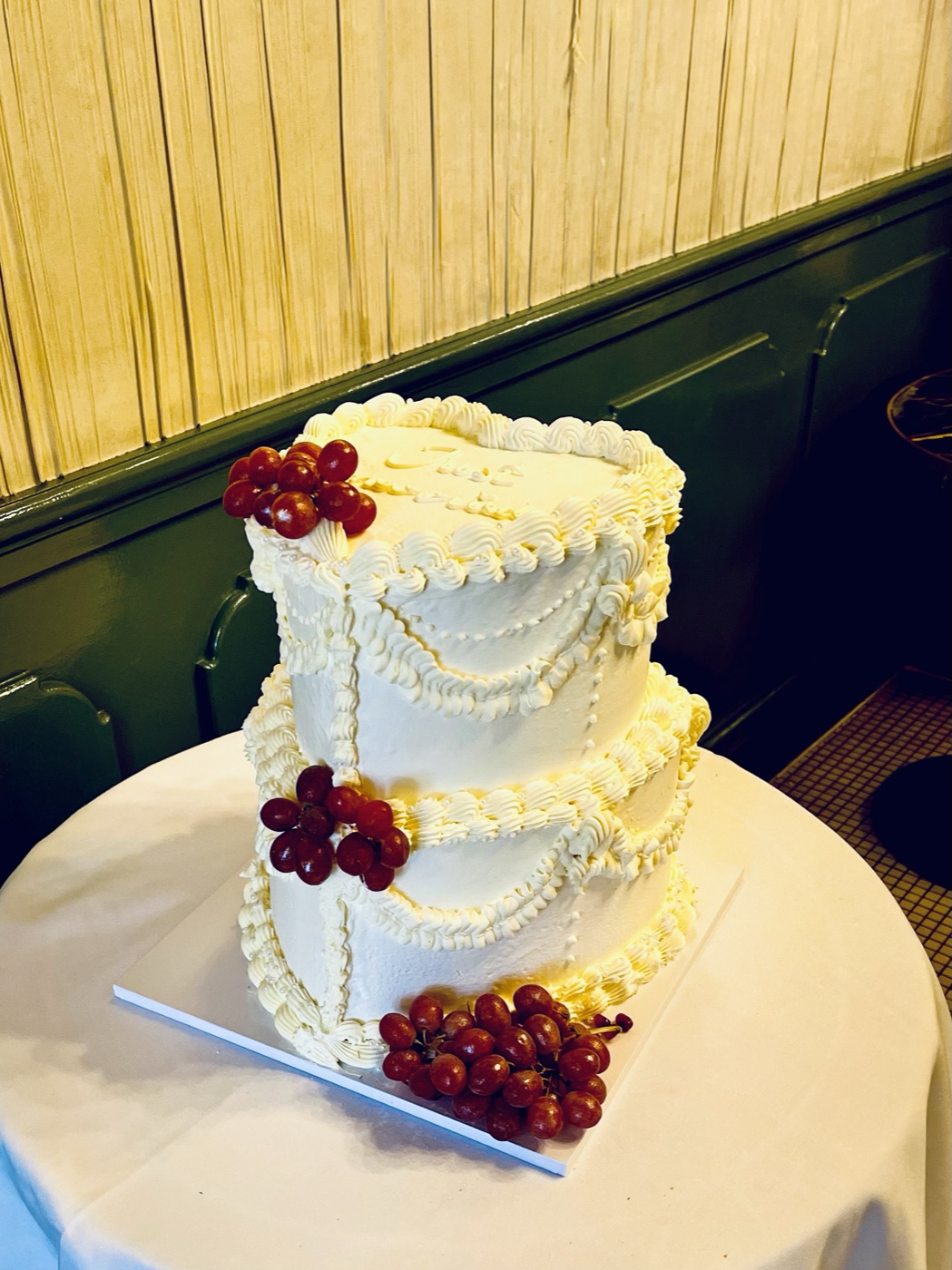 Two-tier vintage-style buttercream wedding cake decorated with red grapes